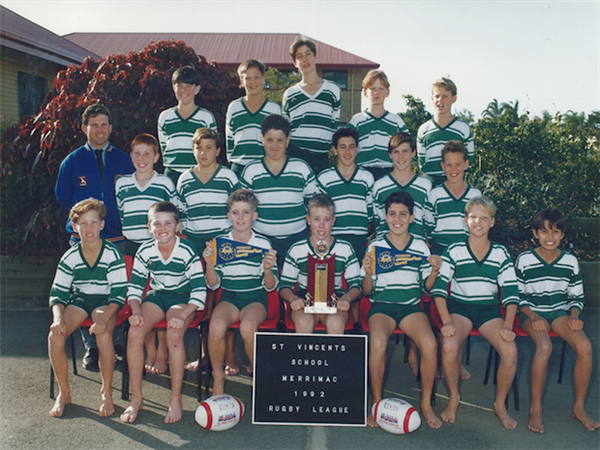Historical school rugby league team photo with students in uniform holding a trophy, representing sporting achievement and school community history