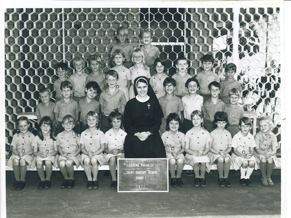 Historical class photo of students with a religious sister seated at the centre representing early Catholic school community life