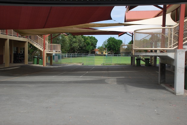 Covered outdoor court with shade sails and open space for sport and play within the school grounds