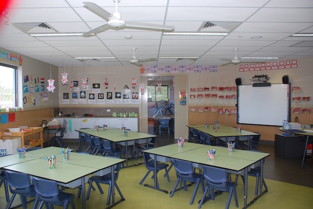 Primary classroom with grouped desks, learning displays and interactive whiteboard supporting collaborative learning