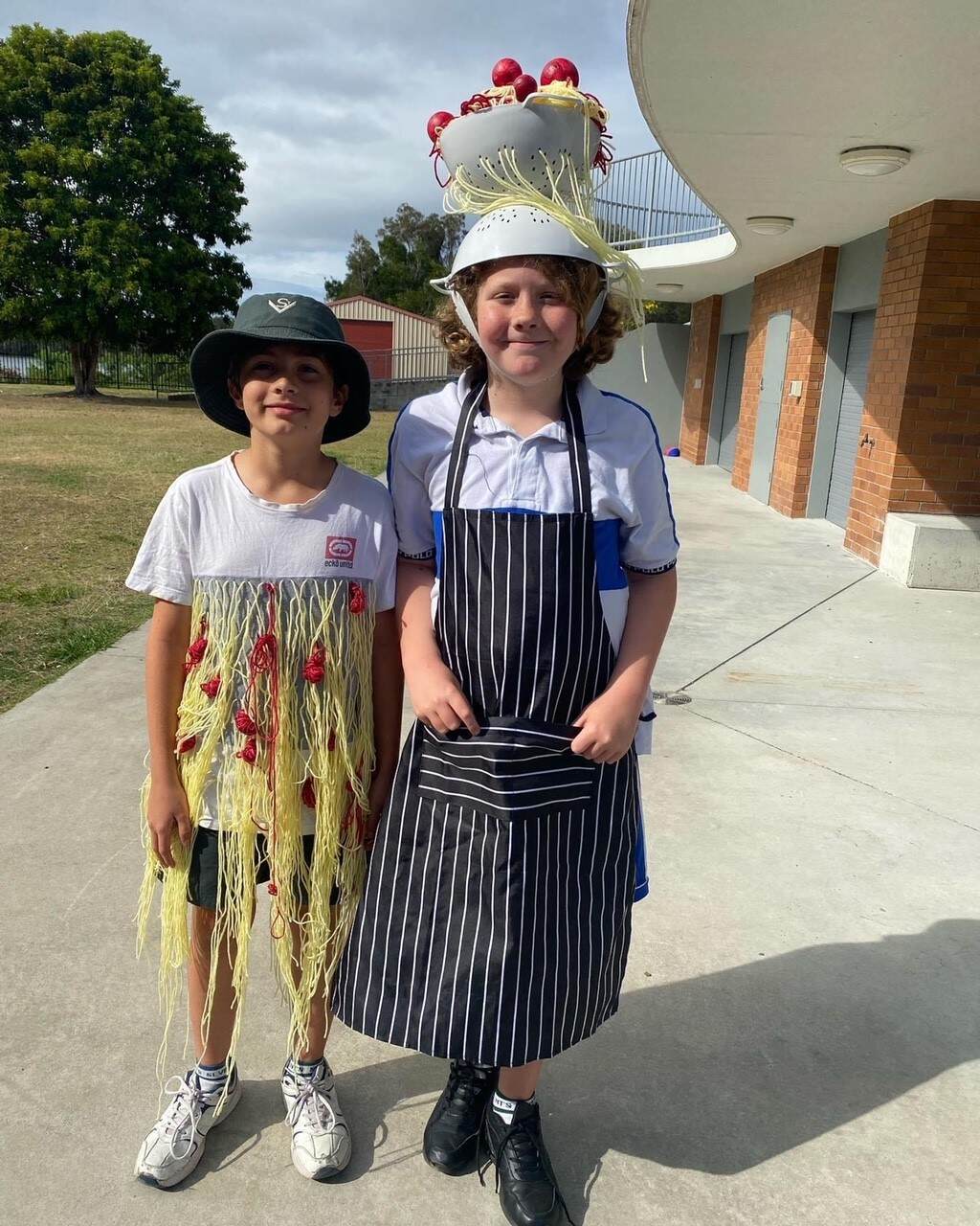 Primary school students dressed in creative food-themed costumes standing outdoors in a school setting.
