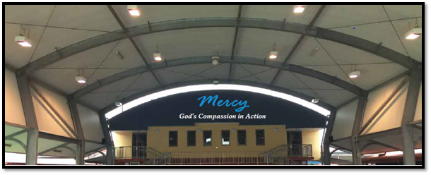 School hall space with Mercy and God’s compassion in action displayed above a stage area