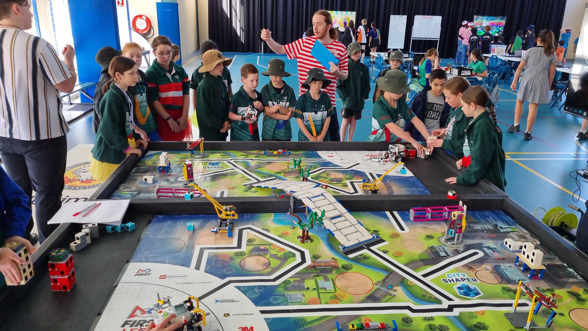 Students gathered around a robotics competition field participating in a hands-on STEM challenge activity