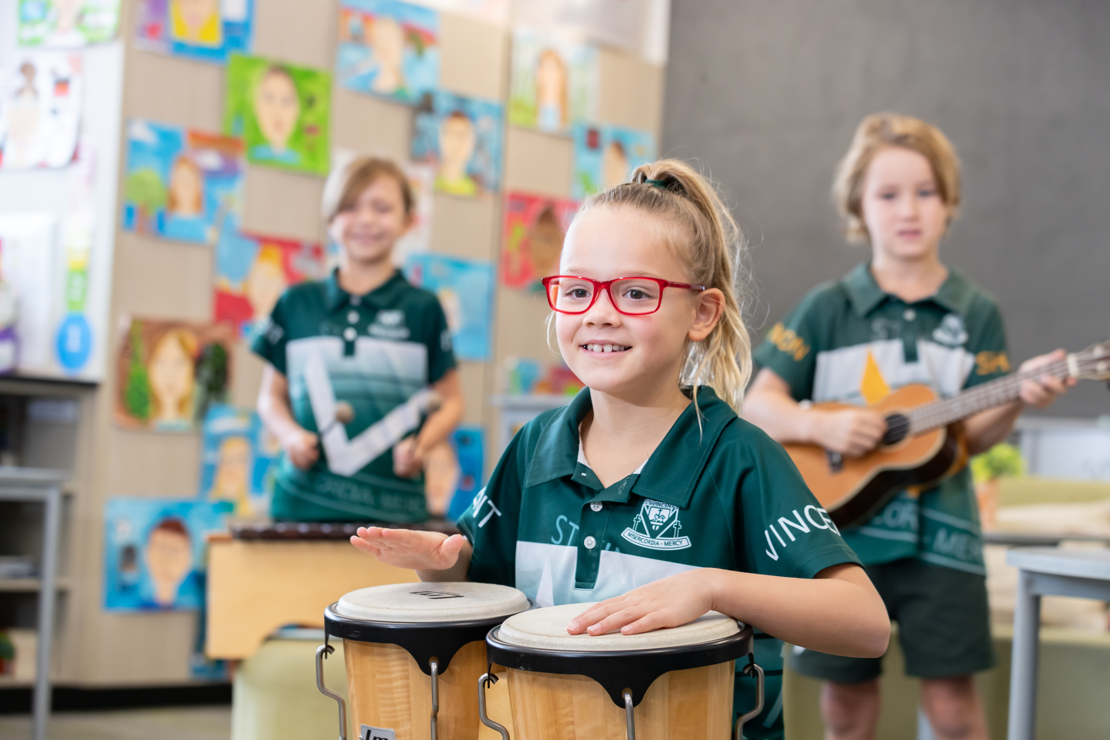 Primary school students participating in a classroom music activity, playing percussion instruments and guitar with student artwork displayed on the wall behind. Provide your feedback on BizChat