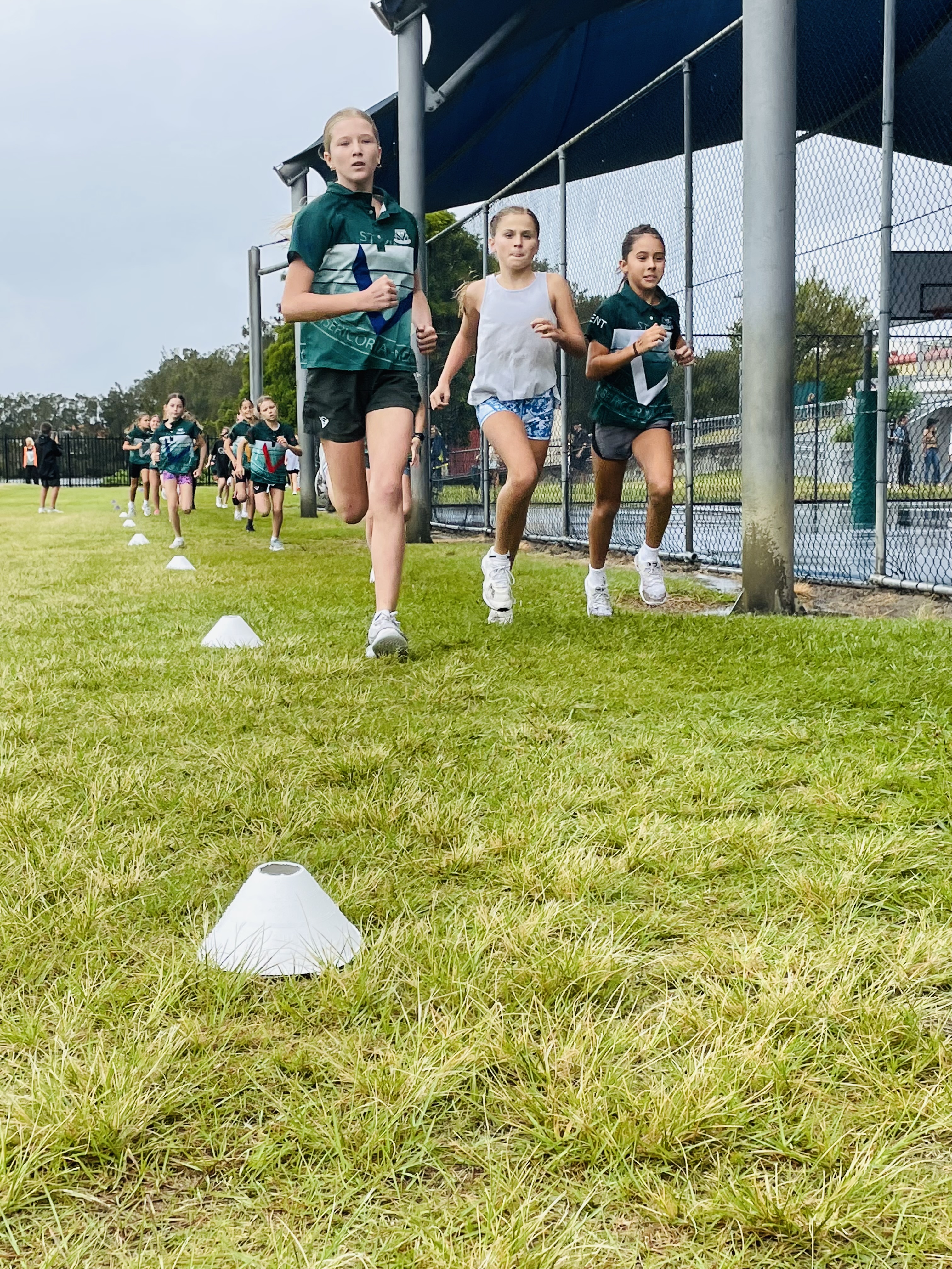 Students participating in a cross country run, moving along a marked course on a grassy field