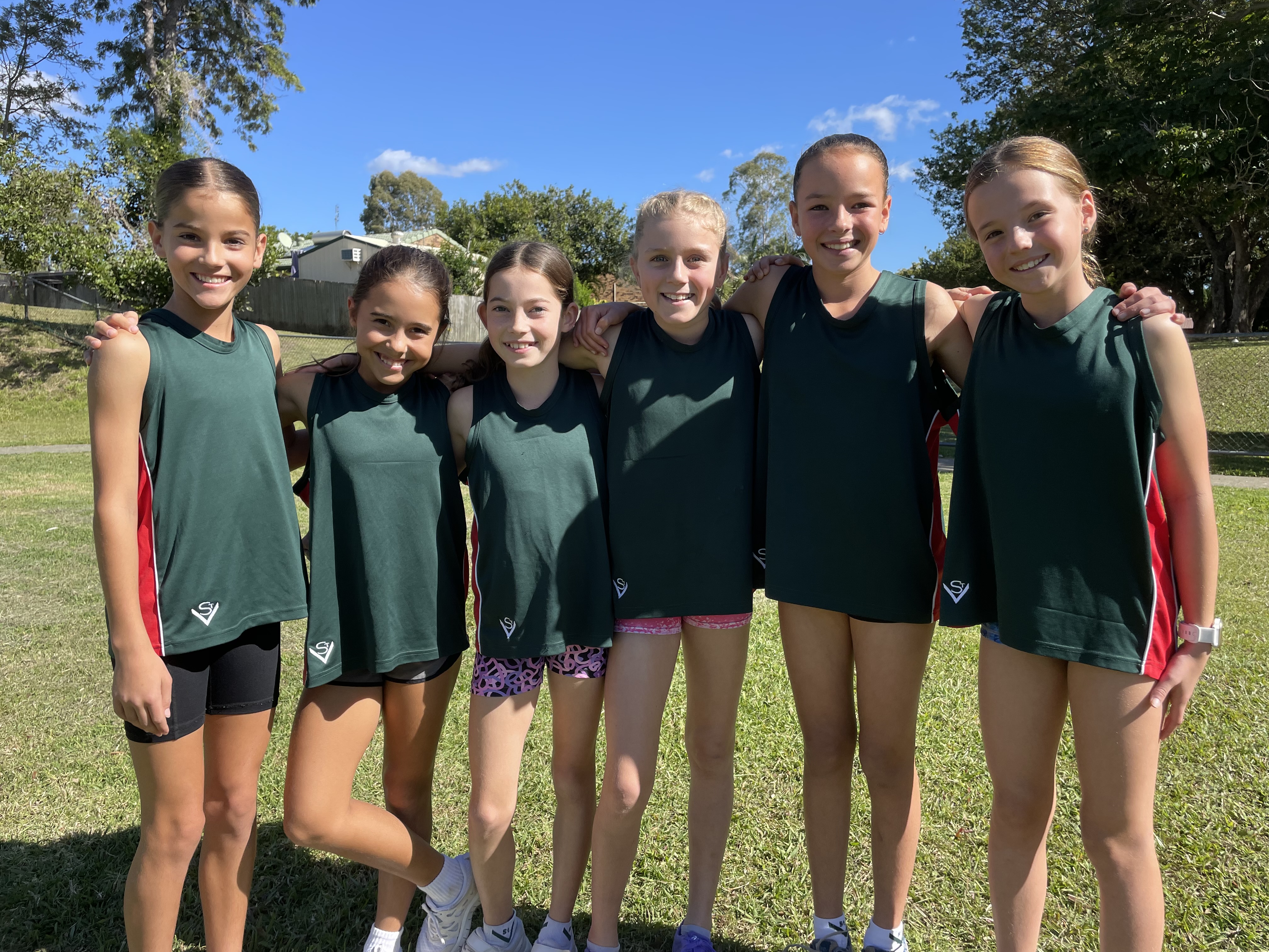 Students posing together on a school field in sports attire as part of a team activity