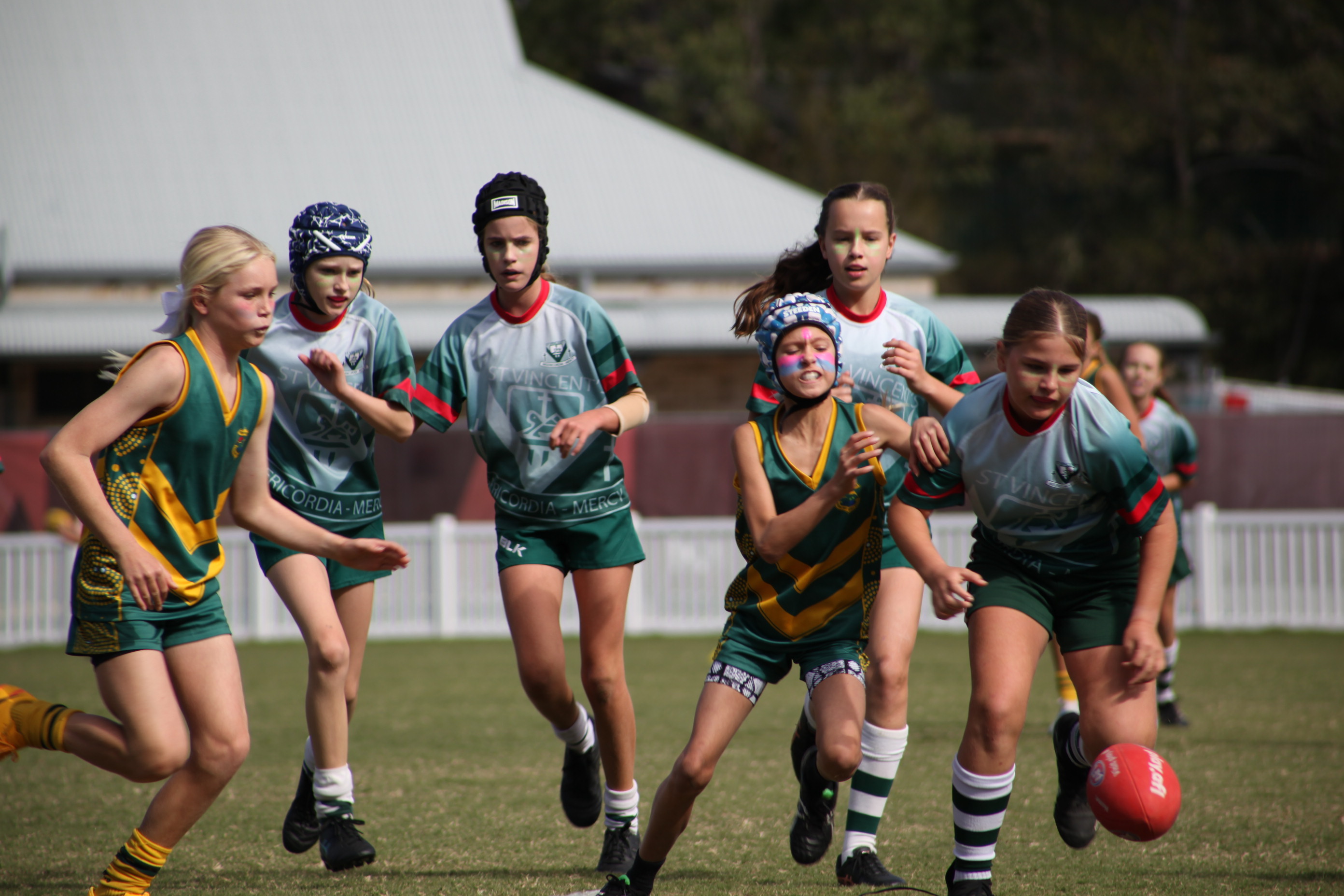 Students standing together outdoors in sports uniforms with arms around each other