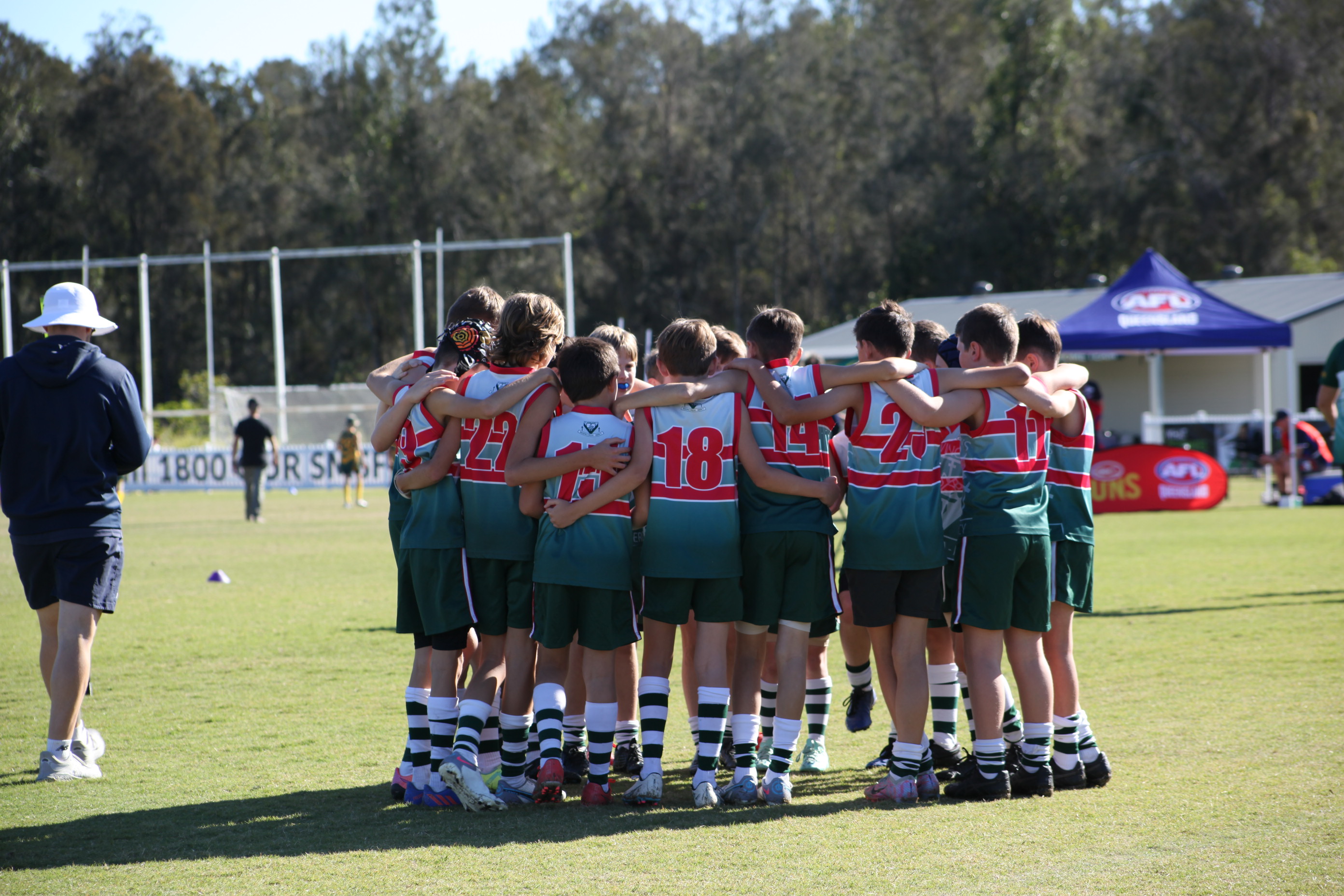 Students in school sports uniforms standing together on a field in a team huddle during an outdoor sports activity