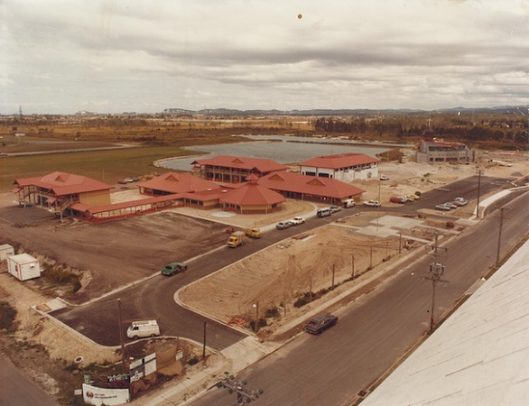 Aerial view of a developing school campus with new buildings, surrounding roads, and open land in the early stages of construction